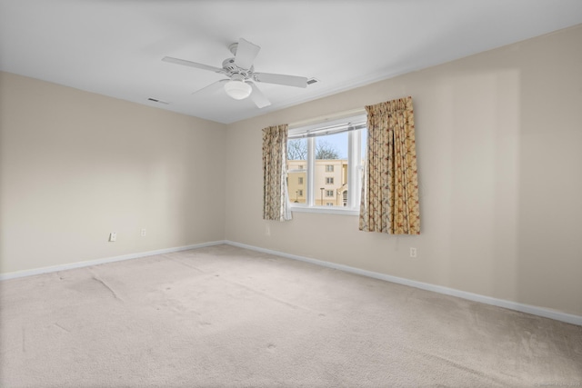 unfurnished room with a ceiling fan, light carpet, visible vents, and baseboards