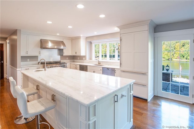 kitchen featuring light stone countertops, white cabinets, and exhaust hood