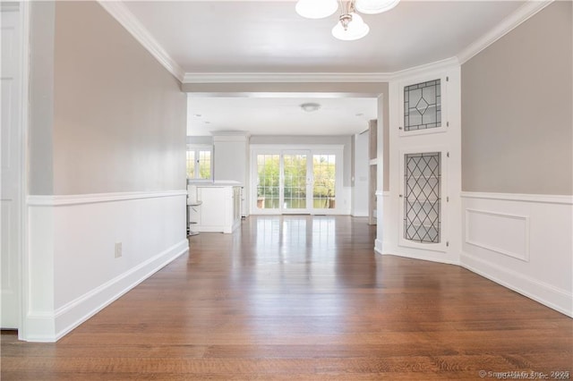 foyer with a chandelier, a decorative wall, a wainscoted wall, wood finished floors, and crown molding