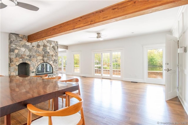 living room with ceiling fan, a fireplace, beam ceiling, and a wealth of natural light