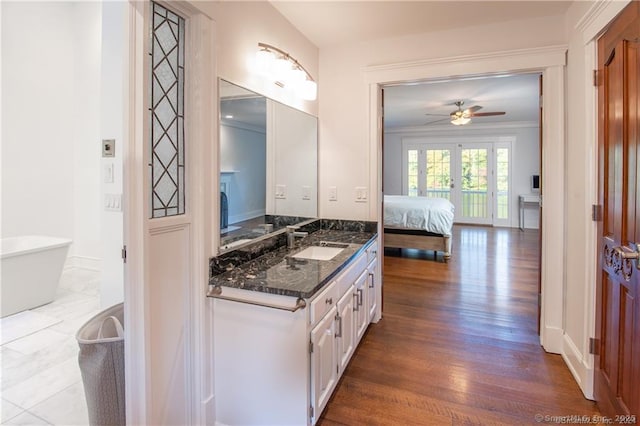 bathroom featuring connected bathroom, wood finished floors, vanity, a ceiling fan, and a freestanding bath