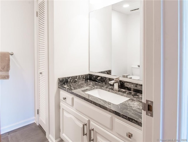 bathroom with toilet, a closet, vanity, and baseboards