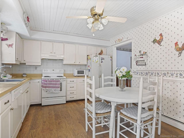 kitchen with white appliances, wallpapered walls, light countertops, under cabinet range hood, and a sink