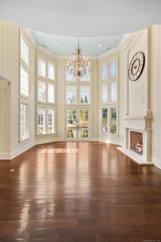 unfurnished living room featuring wood-type flooring, crown molding, a high ceiling, and a premium fireplace