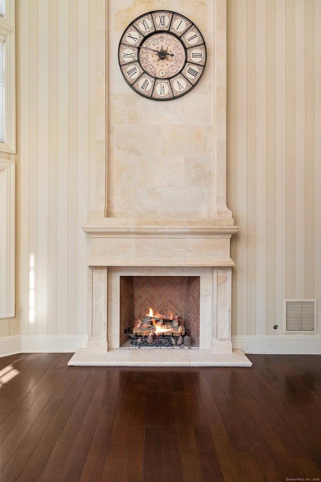 details with a premium fireplace, wood finished floors, visible vents, and baseboards