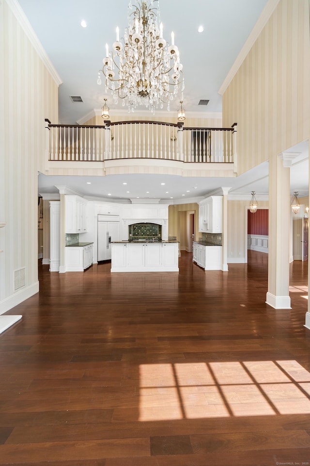 unfurnished living room featuring wallpapered walls, visible vents, ornamental molding, and a chandelier