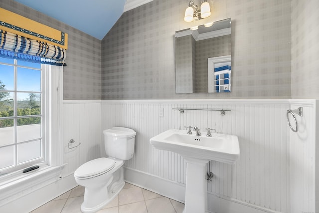 bathroom featuring lofted ceiling, toilet, wainscoting, tile patterned floors, and wallpapered walls