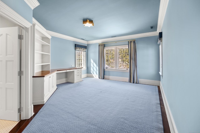 office featuring carpet floors, visible vents, baseboards, ornamental molding, and built in study area