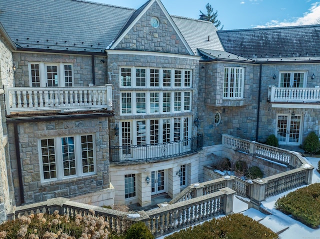 back of house with french doors, a high end roof, and a balcony