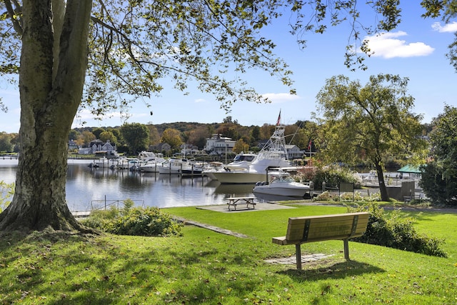 exterior space with a lawn, a boat dock, and a water view