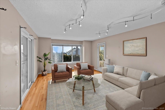 living room featuring light wood-style flooring, baseboards, and a textured ceiling