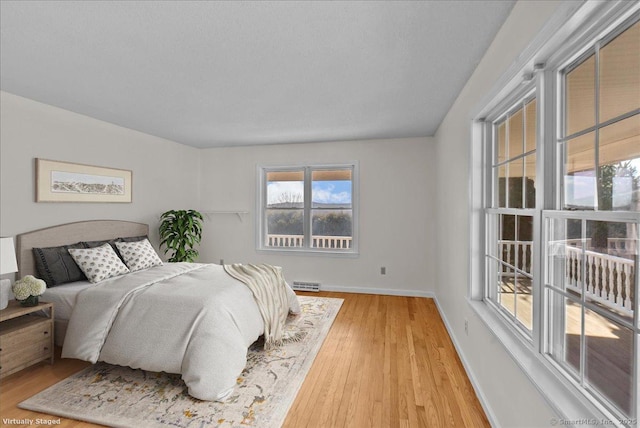 bedroom featuring light wood-type flooring, baseboards, and baseboard heating