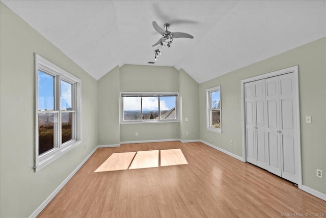 interior space featuring lofted ceiling, ceiling fan, baseboards, and wood finished floors