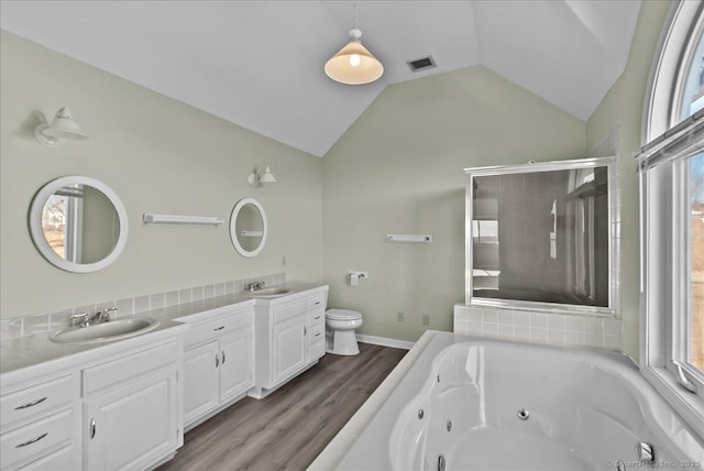 full bathroom featuring lofted ceiling, a jetted tub, toilet, and a sink