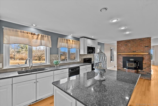 kitchen featuring black appliances, light wood-style floors, a sink, and white cabinets