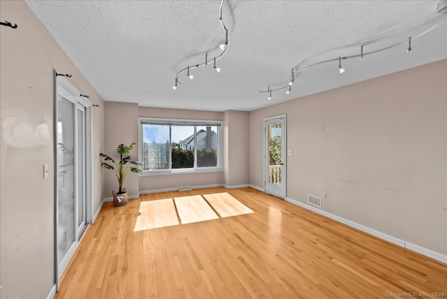 workout area with visible vents, a textured ceiling, baseboards, and wood finished floors