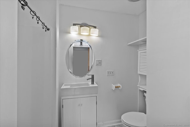 bathroom with toilet, vanity, and baseboards