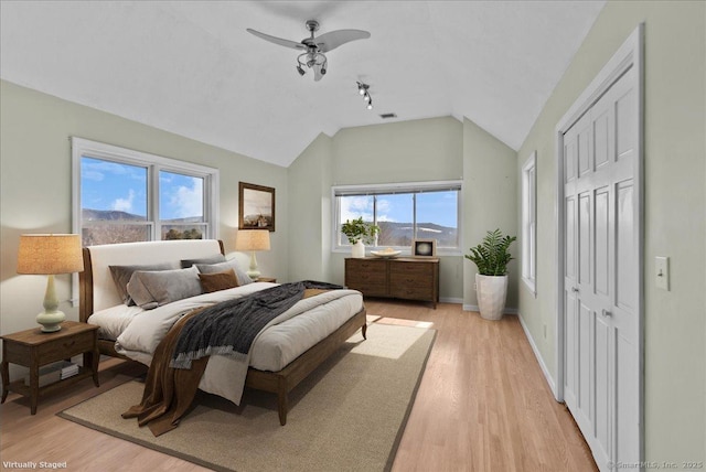 bedroom with light wood-type flooring, visible vents, baseboards, and lofted ceiling