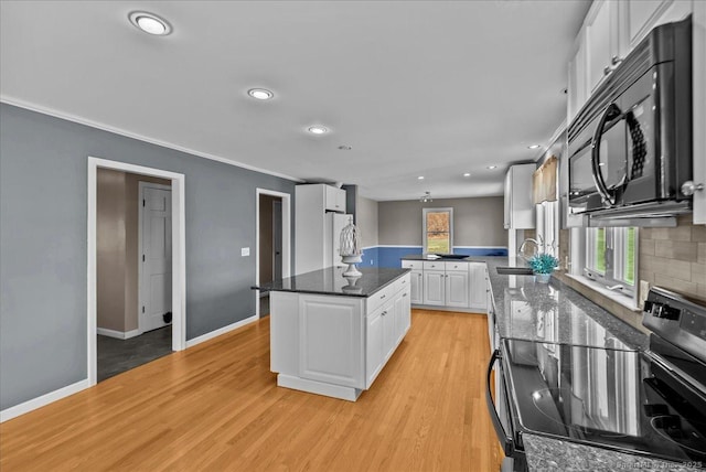 kitchen featuring black microwave, white cabinetry, electric stove, light wood-type flooring, and freestanding refrigerator