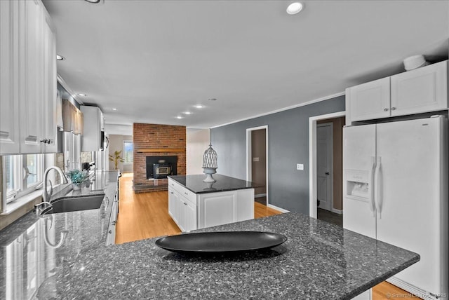 kitchen featuring light wood-style floors, white cabinetry, a sink, a kitchen island, and white fridge with ice dispenser