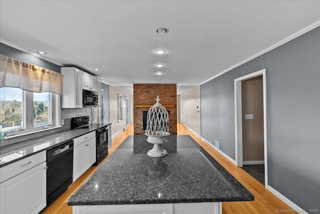 kitchen featuring visible vents, light wood-style flooring, a kitchen island, black appliances, and white cabinetry