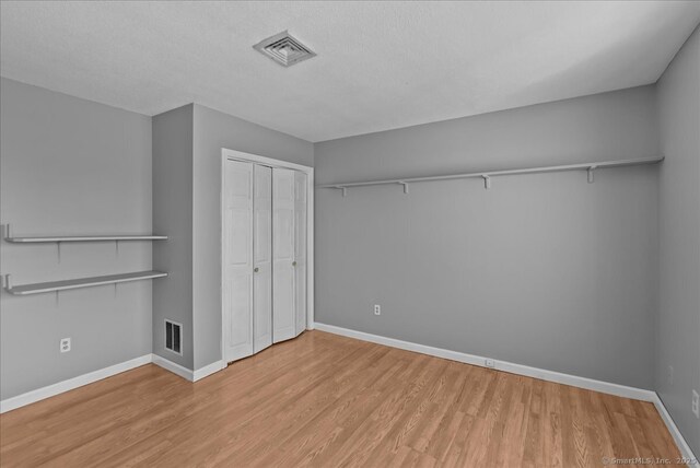 unfurnished bedroom featuring a closet, wood finished floors, visible vents, and baseboards