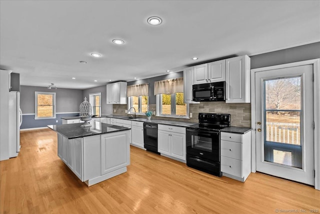 kitchen with dark countertops, white cabinets, a sink, and black appliances