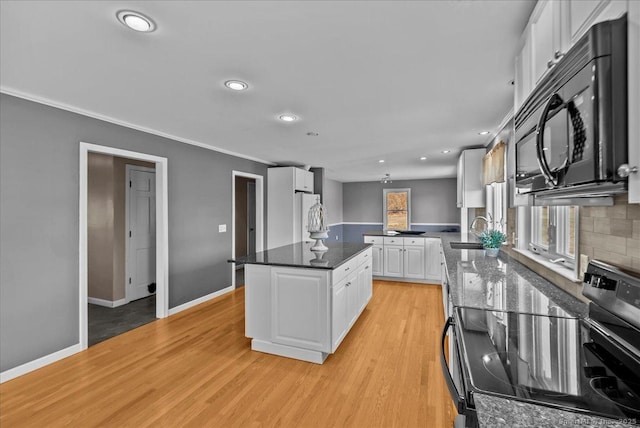 kitchen with black microwave, white cabinetry, light wood-style floors, freestanding refrigerator, and stainless steel electric stove