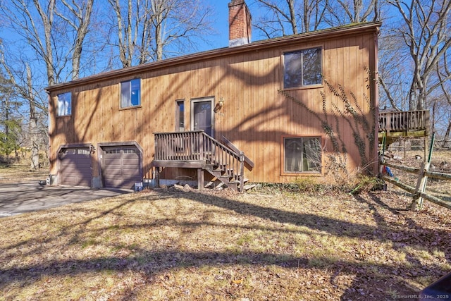 exterior space with an attached garage, a chimney, and concrete driveway