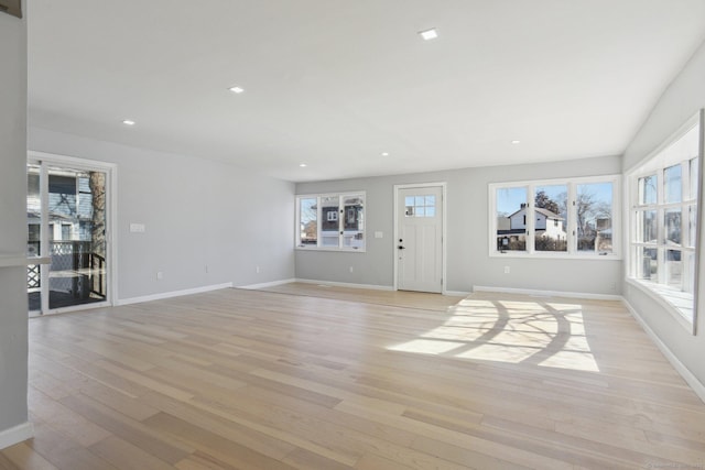 unfurnished living room with a healthy amount of sunlight, light wood-style floors, baseboards, and recessed lighting