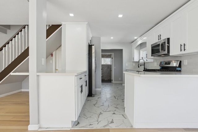 kitchen featuring decorative backsplash, marble finish floor, stainless steel appliances, light countertops, and white cabinetry