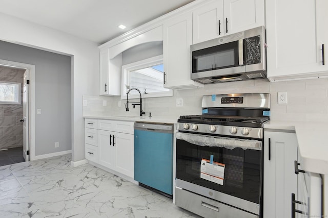 kitchen featuring marble finish floor, white cabinetry, stainless steel appliances, and light countertops