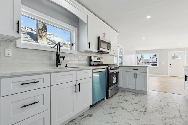 kitchen with marble finish floor, stainless steel appliances, recessed lighting, white cabinets, and a sink