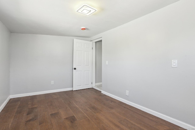 spare room featuring dark wood-type flooring and baseboards