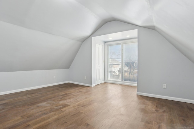 additional living space with vaulted ceiling, wood finished floors, and baseboards