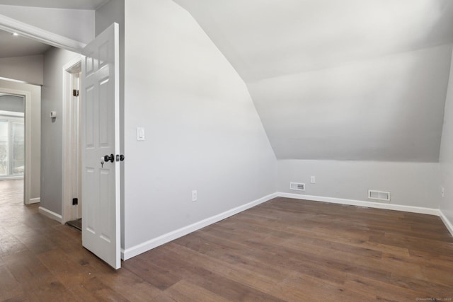 additional living space with lofted ceiling, baseboards, visible vents, and dark wood-type flooring