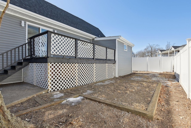 view of side of home with roof with shingles and fence