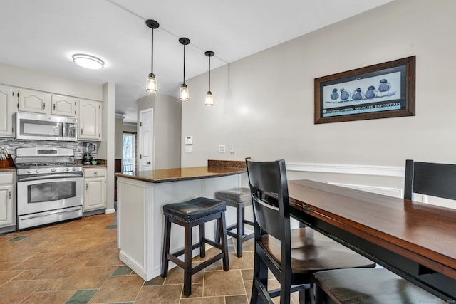 kitchen with tasteful backsplash, a peninsula, appliances with stainless steel finishes, and white cabinets