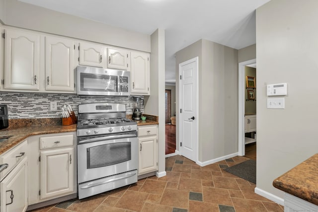 kitchen with stone finish floor, white cabinetry, appliances with stainless steel finishes, and decorative backsplash