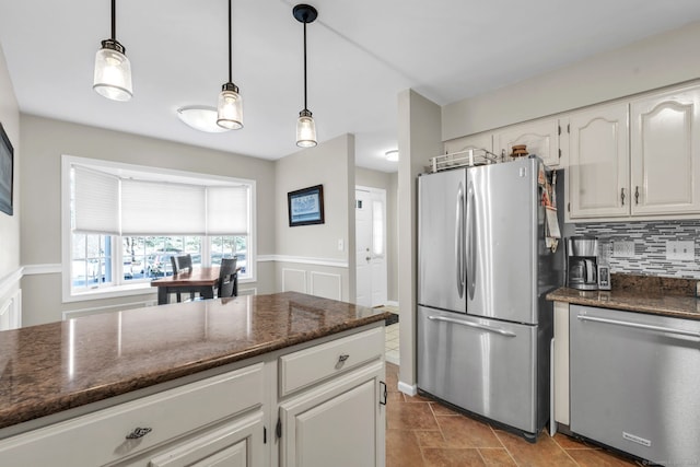 kitchen featuring stainless steel appliances, white cabinets, decorative backsplash, dark stone countertops, and decorative light fixtures