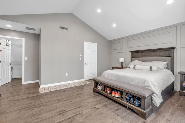 bedroom with lofted ceiling, baseboards, visible vents, and wood finished floors