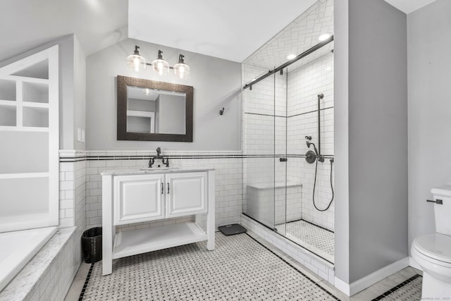 bathroom with a stall shower, toilet, tile walls, and vanity