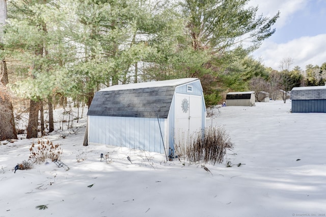 snow covered structure with an outbuilding and a storage shed