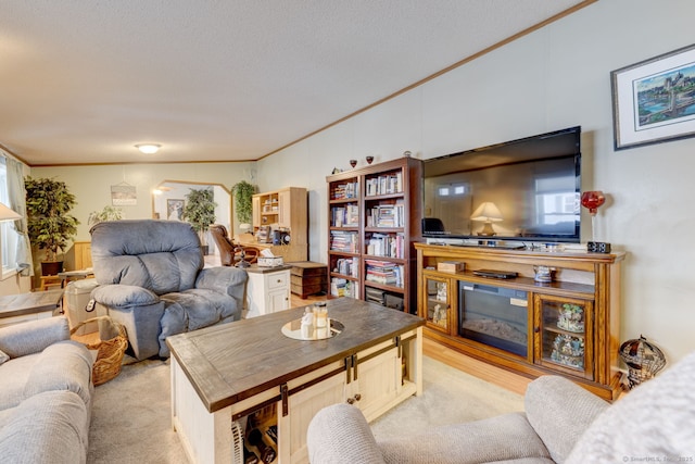 living room featuring light carpet, a textured ceiling, a fireplace, and crown molding