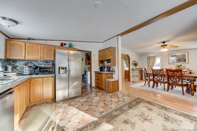 kitchen with appliances with stainless steel finishes, light countertops, crown molding, and backsplash