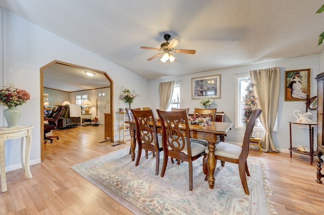 dining room featuring light wood-style floors, ceiling fan, baseboards, and a textured ceiling