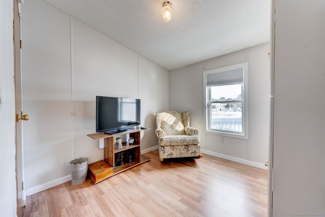 sitting room with a textured ceiling, wood finished floors, and baseboards