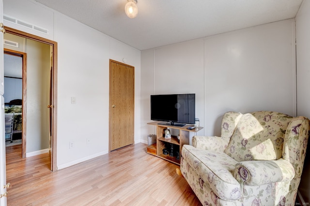 living area with baseboards, visible vents, and light wood finished floors