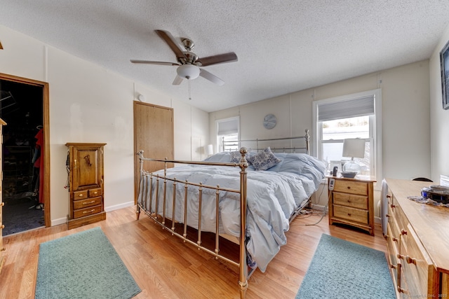 bedroom featuring light wood-type flooring, a ceiling fan, and a textured ceiling