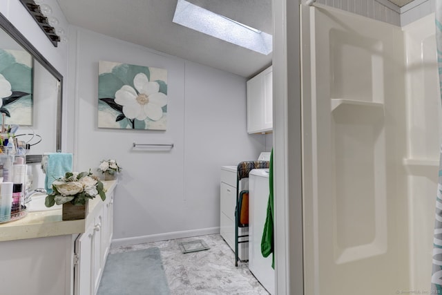 laundry room featuring a skylight, cabinet space, a textured ceiling, washer and dryer, and baseboards